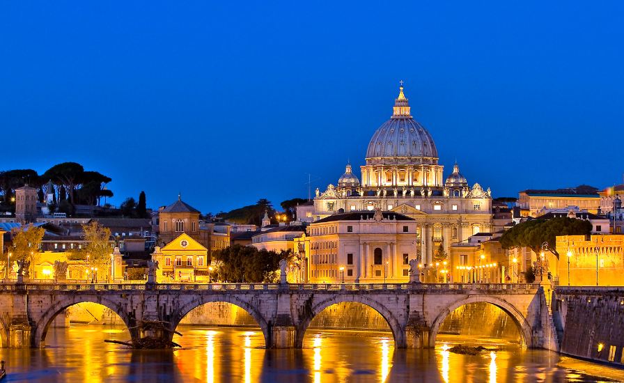 Night view of Rome with St. Peter's Basilica's dome in the background, showcasing the city's beauty and iconic landmark

