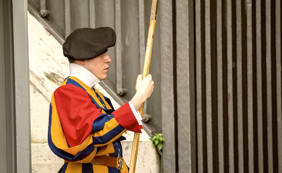 A Swiss Guard of St. Peter's Basilica dressed in a costume, holding a stick.
